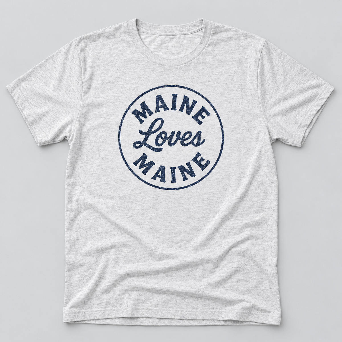 The Beacon Tee in Heather White with navy Maine Loves Maine distressed circle logo, approved flat lay