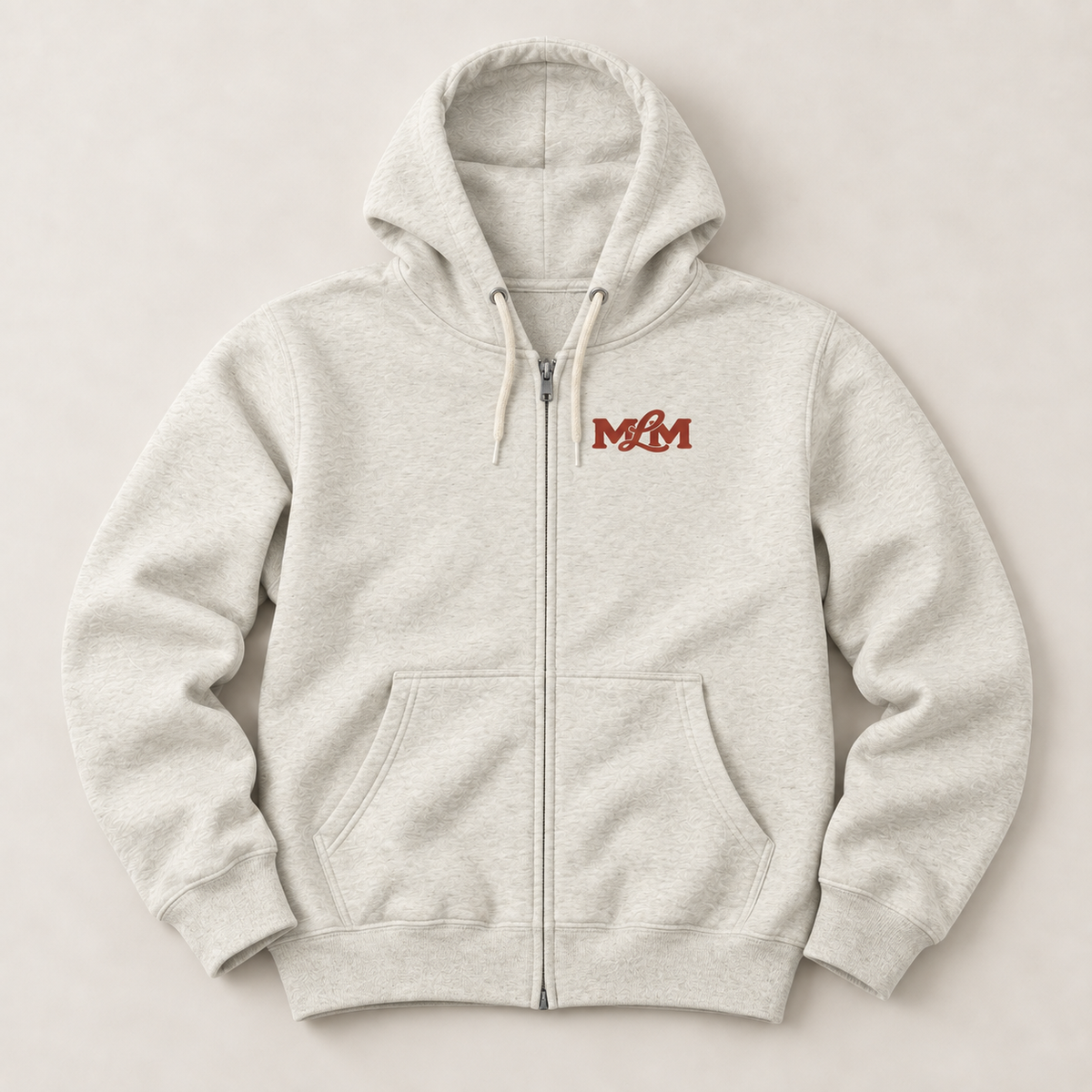 The Campfire Zip Hoodie in Oatmeal Heather with rust MLM monogram, flat lay